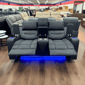 Black two seater recliner sofa with cup holders, storage, and blue LED lighting in a showroom