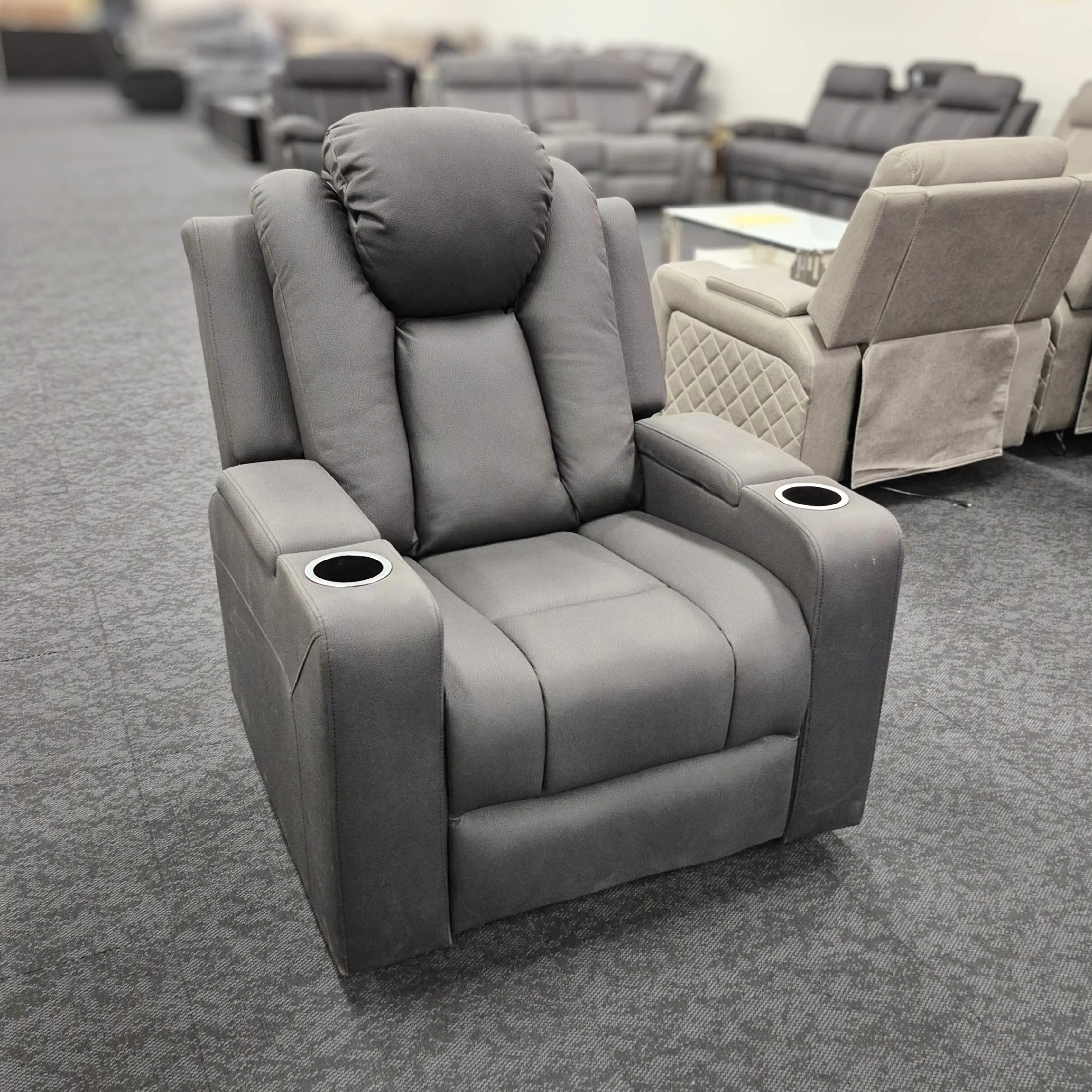Gray dual motor electric recliner chair with cup holders on display in a showroom