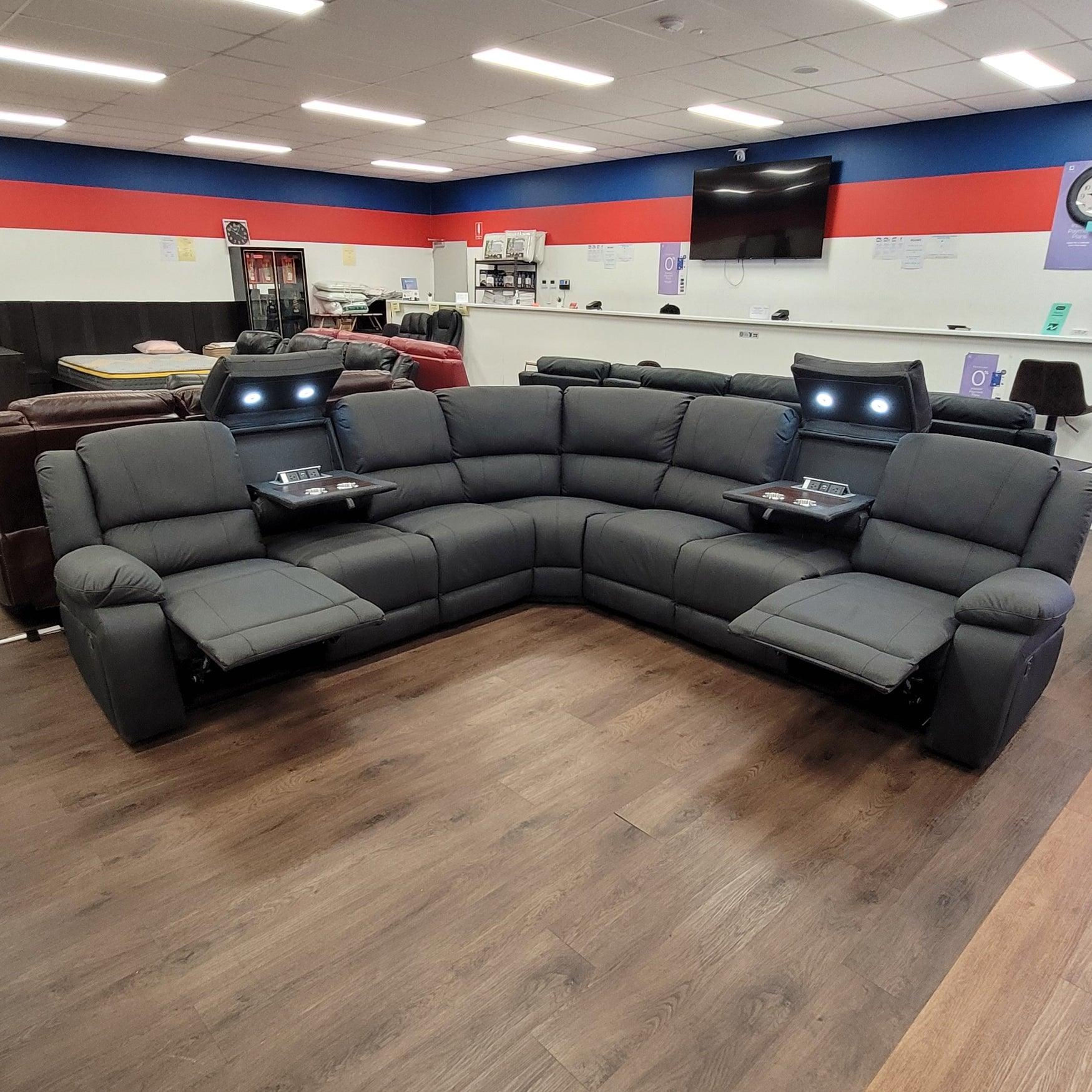 Modern black reclining sectional sofa with cup holders and LED lights in showroom
