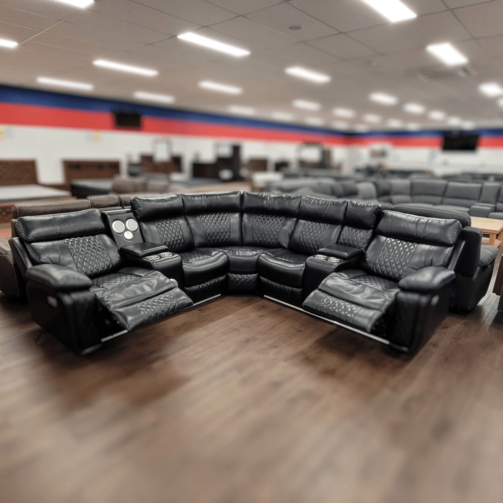 Black leather corner recliner lounge set with cup holders on showroom floor