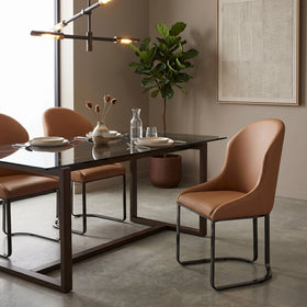 Darkwood Brown Dining Chair in warm brown PU faux leather with a curved high back and slim black metal sled legs, styled beside a glass-top dining table - The A2Z Furniture