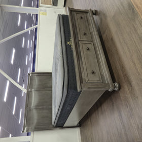 The A2Z Furniture showroom floor display of the Canada Bed Frame in grey, three-quarter view showing the sleigh-style headboard and panelled footboard with two storage drawers (mattress shown, not included).