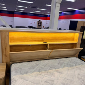 Canberra gas lift bed frame headboard in pale oak, front view showing the LED-lit display shelf and push-open storage compartments - The A2Z Furniture showroom
