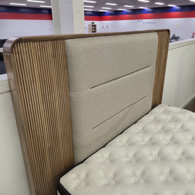 Close angled detail of the Castle Bed Frame headboard showing the fluted natural timber side panel, rounded corner and beige upholstered channel panel, in The A2Z Furniture showroom.