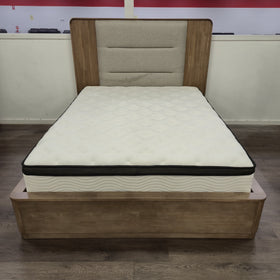 Castle Bed Frame in a natural timber finish with beige upholstered headboard panel, viewed from the foot of the bed in The A2Z Furniture showroom. Mattress shown is not included.