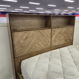 Bookcase headboard of the Cleveland Bookcase Bed Frame in a light natural timber finish, with open shelf compartments and two parquet-panelled hinged doors, in The A2Z Furniture showroom. Mattress shown is not included.