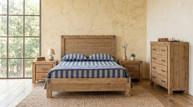 Wooden bed with striped bedding in a bedroom setting with furniture and decor.