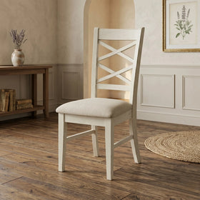 White wooden chair with a cushioned seat in a room with wooden flooring and a small table.