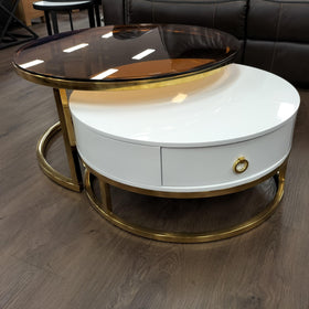 Modern coffee table set with smoked glass top and white drawer, gold metal frame, on wood floor