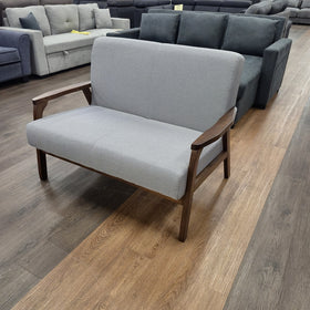 Donald 2 Seater Fabric Sofa in light grey shown from a three-quarter angle, showing the two-seat cushion, timber legs and curved armrests, in The A2Z Furniture showroom