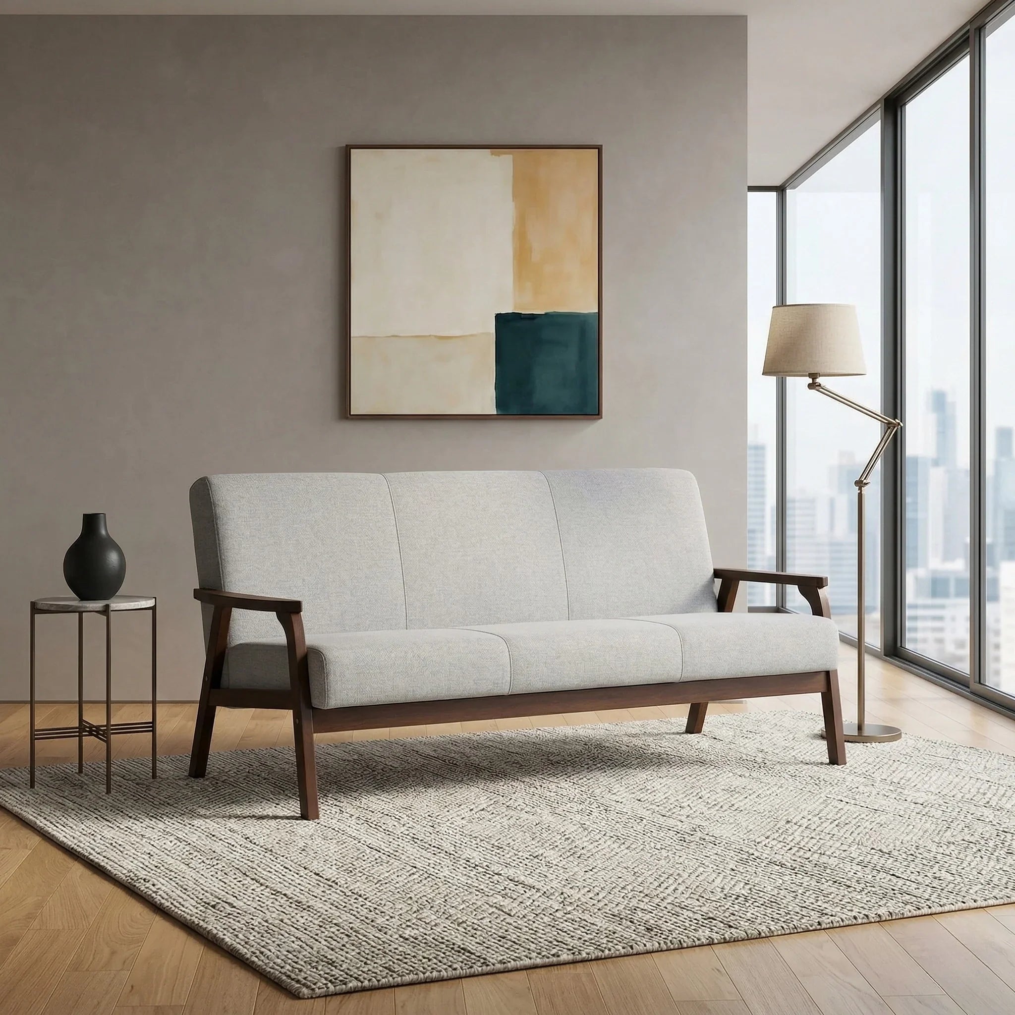 Donald 3 Seater Fabric Sofa in light gray with wooden legs and armrests, styled in a modern living room with a floor lamp, abstract wall art, and a textured area rug.