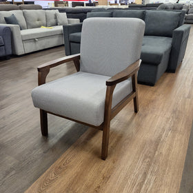 Donald Arm Chair in light grey viewed from the side, showing the timber side rail, seat cushion and padded backrest, in The A2Z Furniture showroom