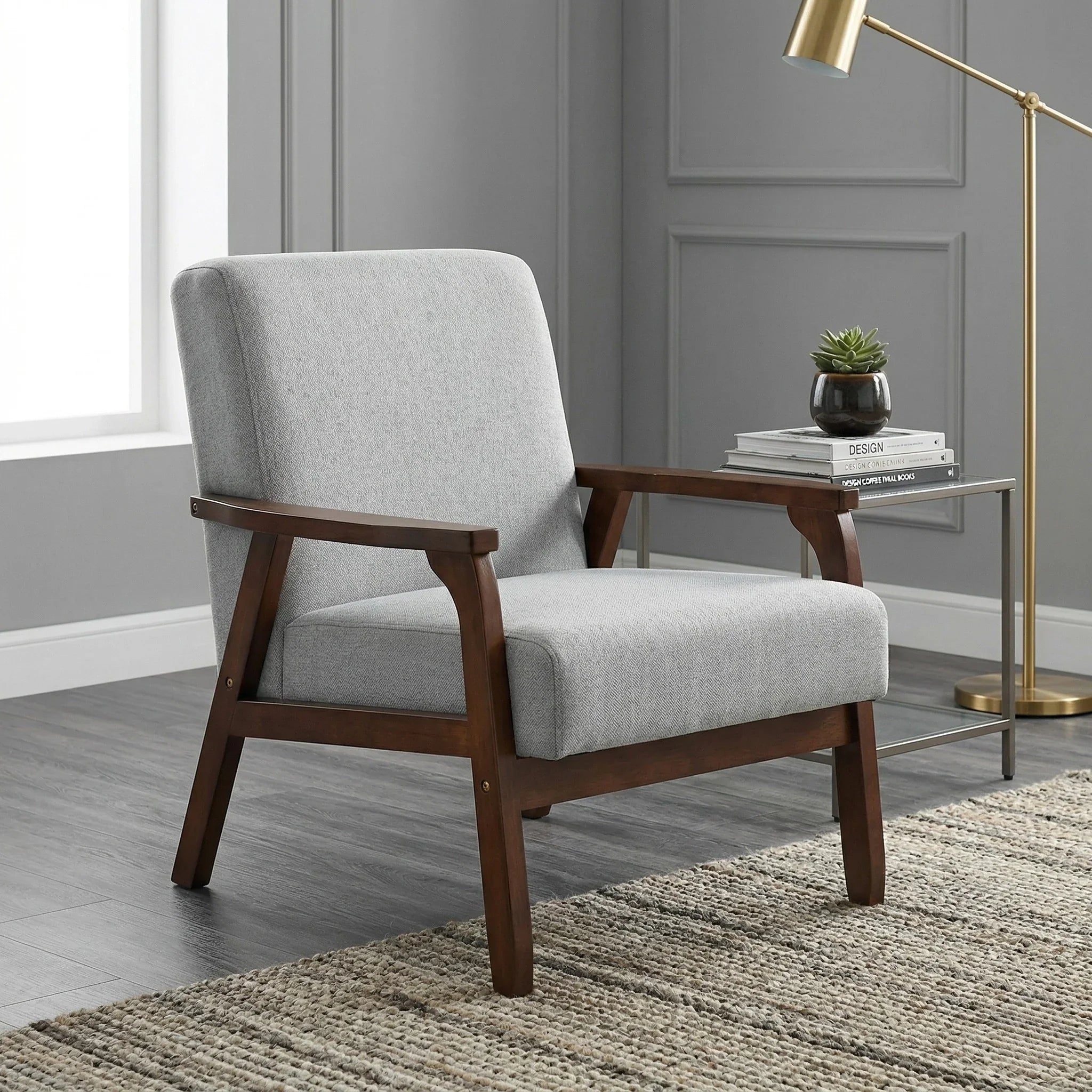Gray upholstered armchair with wooden frame in a room with gray walls and a gold floor lamp.