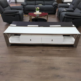 Modern white TV unit with drawers and metal accents in a furniture showroom setting
