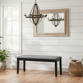 Dining room with a bench, plants, and a mirror on a white wall.