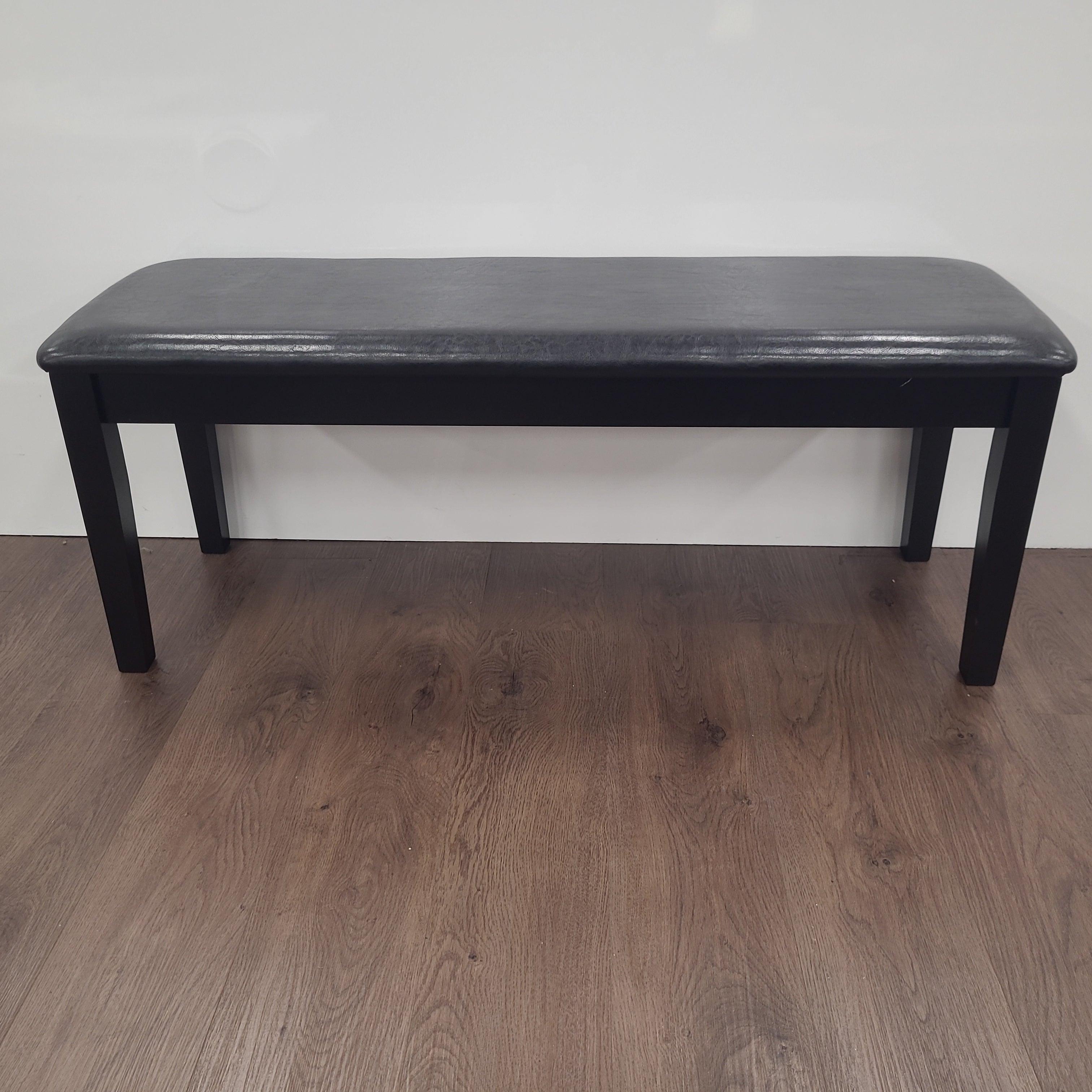 Modern black dining bench with padded seat on wooden floor against white wall