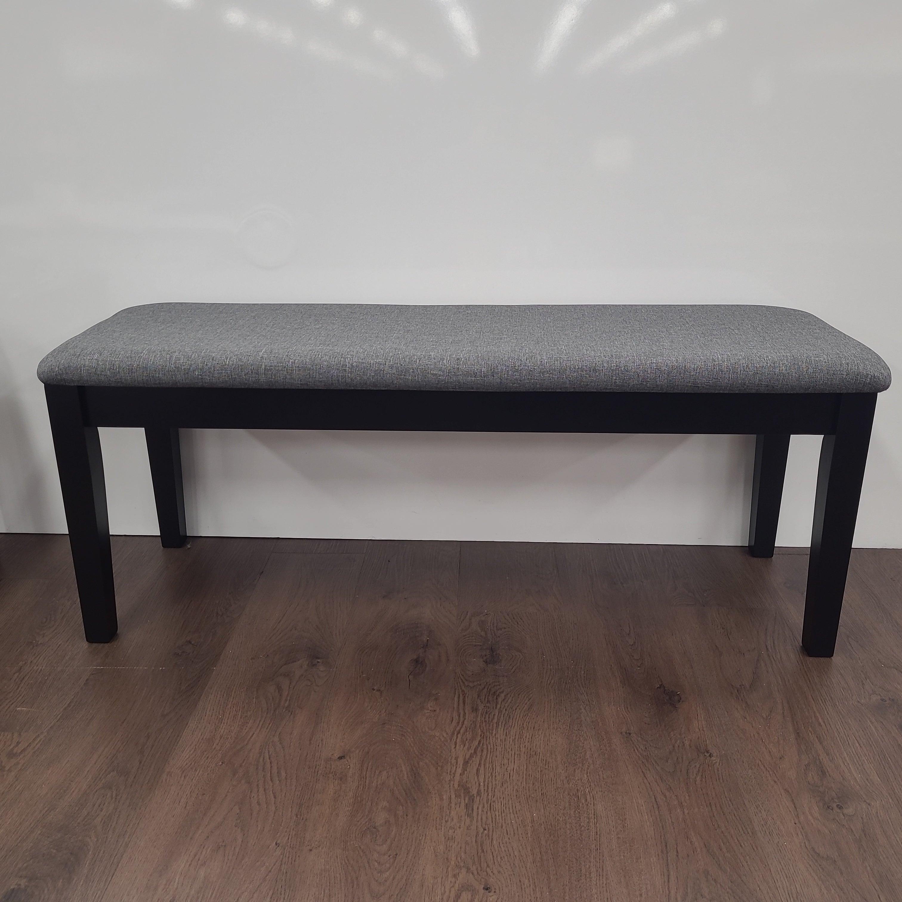 Modern dining bench with grey upholstered seat and black wooden legs on wood floor