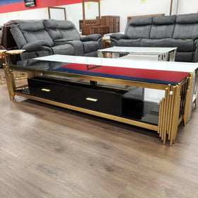Modern glass and gold TV unit with storage drawers displayed in a furniture showroom
