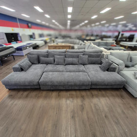 Grey corner sofa with ottoman and cushions in a spacious furniture showroom