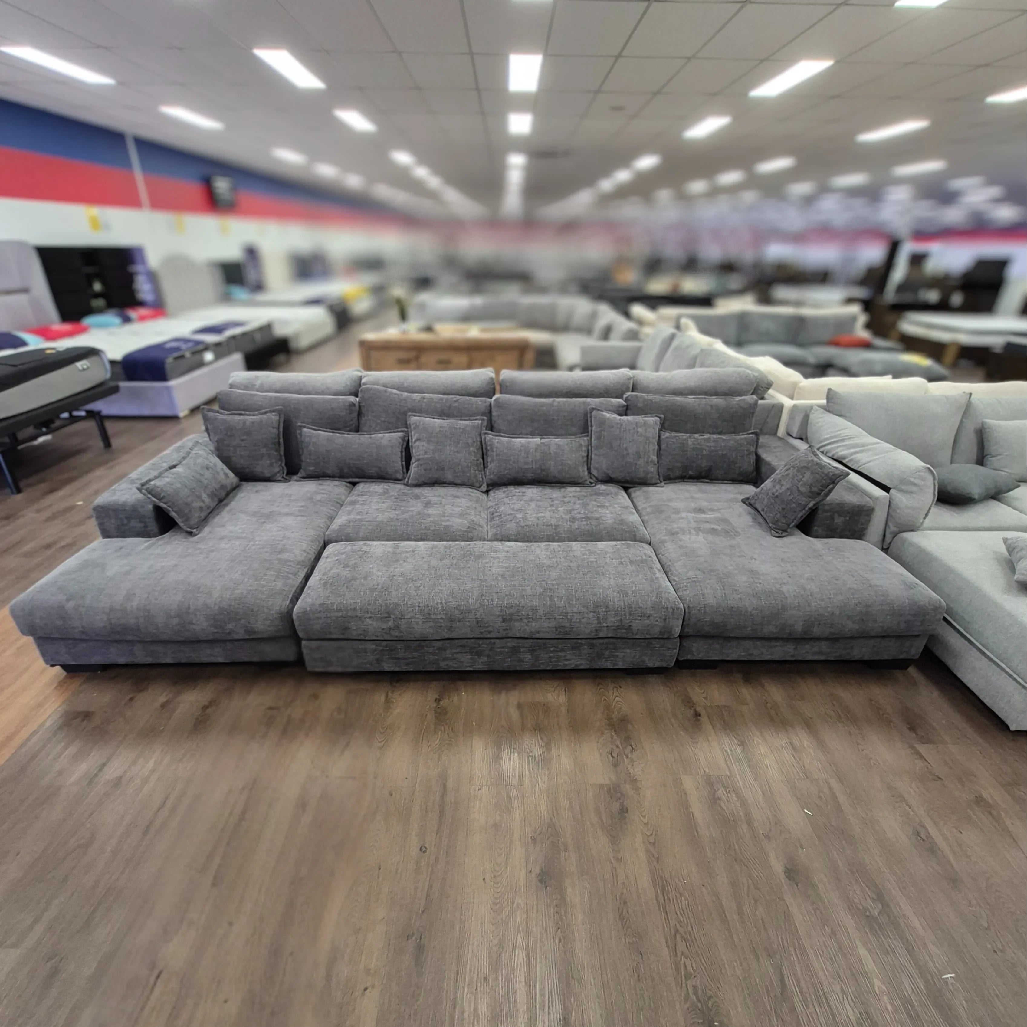 Grey corner sofa with ottoman and cushions in a spacious furniture showroom