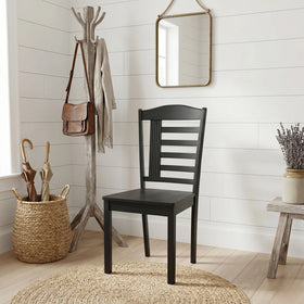 Black chair in a room with a coat rack, mirror, and basket of umbrellas.