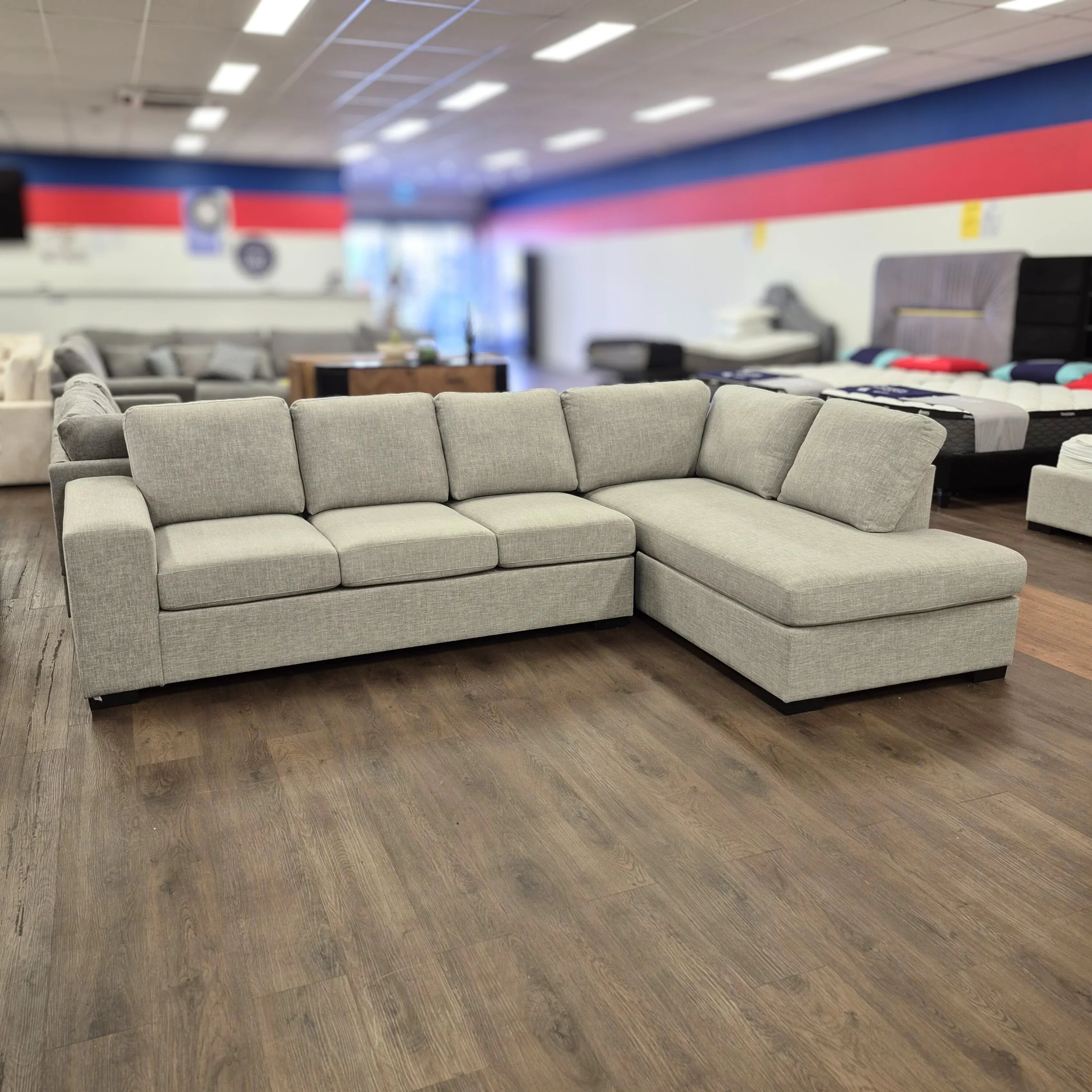 Light grey L-shaped sectional sofa on wood floor in a modern furniture showroom