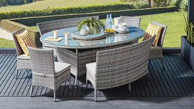 Outdoor wicker dining set with glass top table, curved bench, and striped cushions on patio