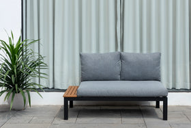 Modern grey outdoor 2-seater sofa with metal frame and wood detail, next to potted plant