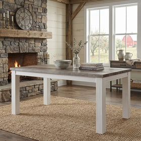 Dining room with a stone fireplace, wooden dining table, and large windows.
