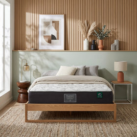 Bedroom with a wooden bed frame and mattress, decorative pillows, and a shelf with decor items.