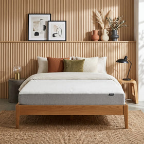 Bedroom with a wooden bed frame, white mattress, and decorative pillows against a wooden wall.
