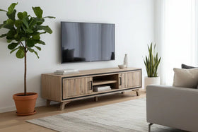 Modern living room with a wooden TV stand, television, and decorative plants.