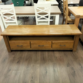 Josh TV Unit made of natural wood with a smooth finish featuring three drawers with metal handles, suitable for organizing and displaying a television in a living room.