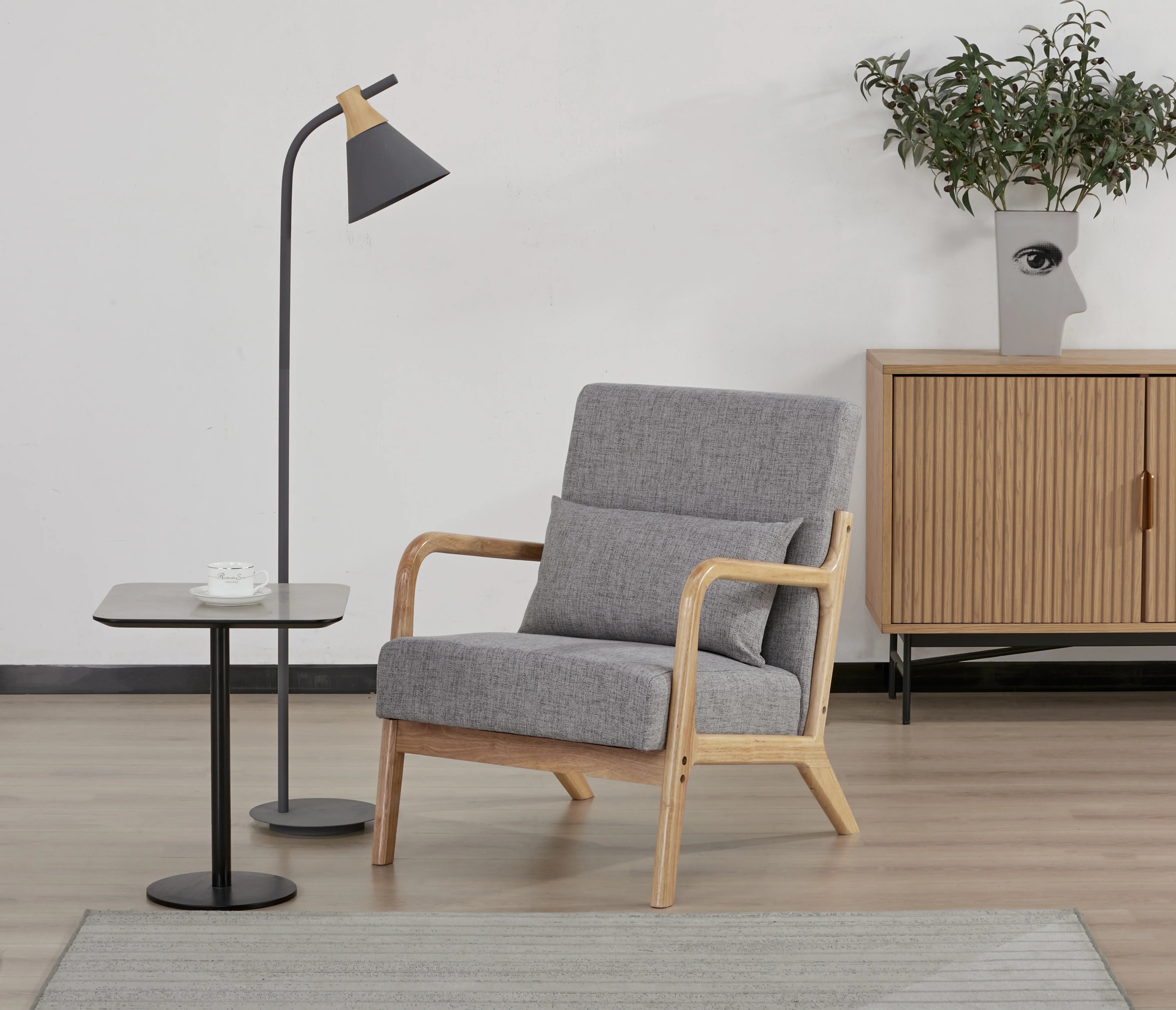 Modern lounge room with grey armchair, wooden sideboard, floor lamp, and side table