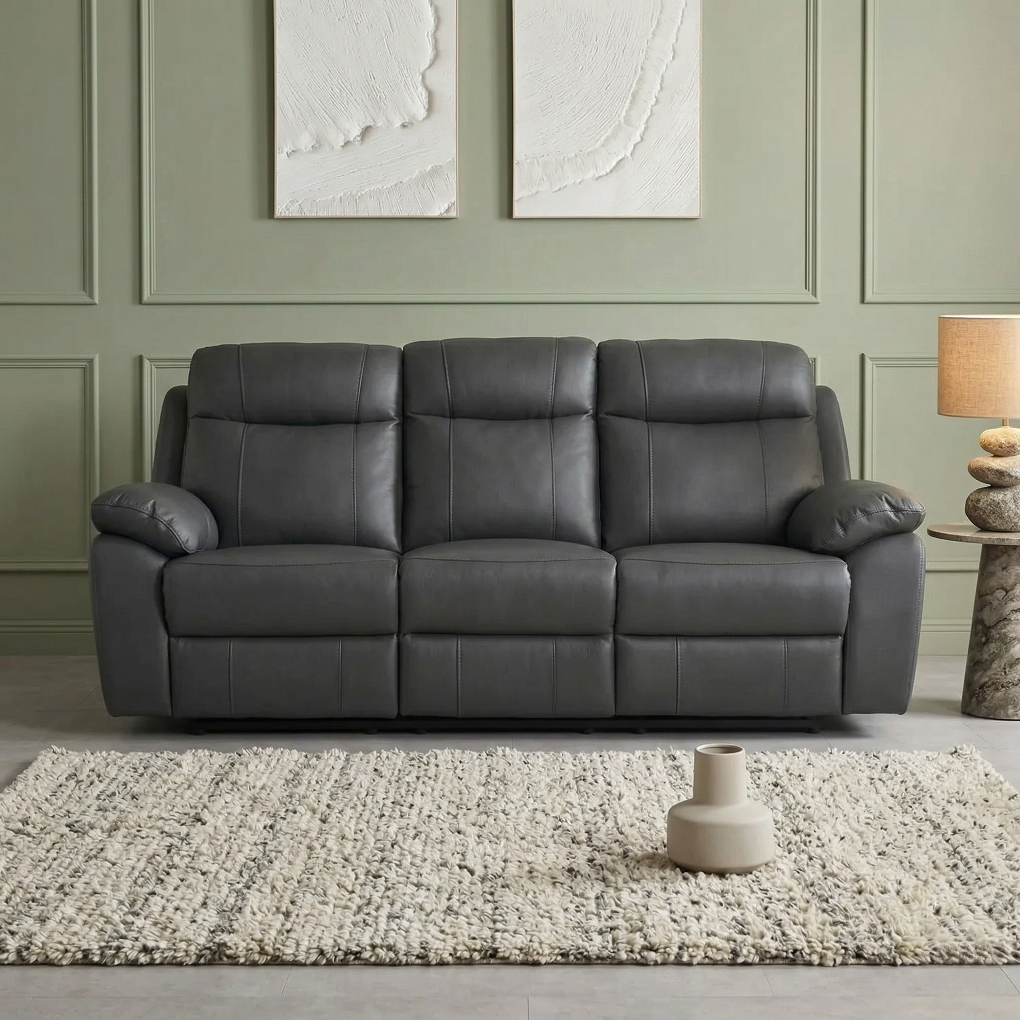 Latrobe 3 Seater Leather Recliner Lounge in dark gray with plush cushions and padded armrests set against a muted green wall with minimalist artwork and a textured beige rug.