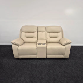 Beige leather two-seater recliner sofa with center console and cup holders on dark carpet