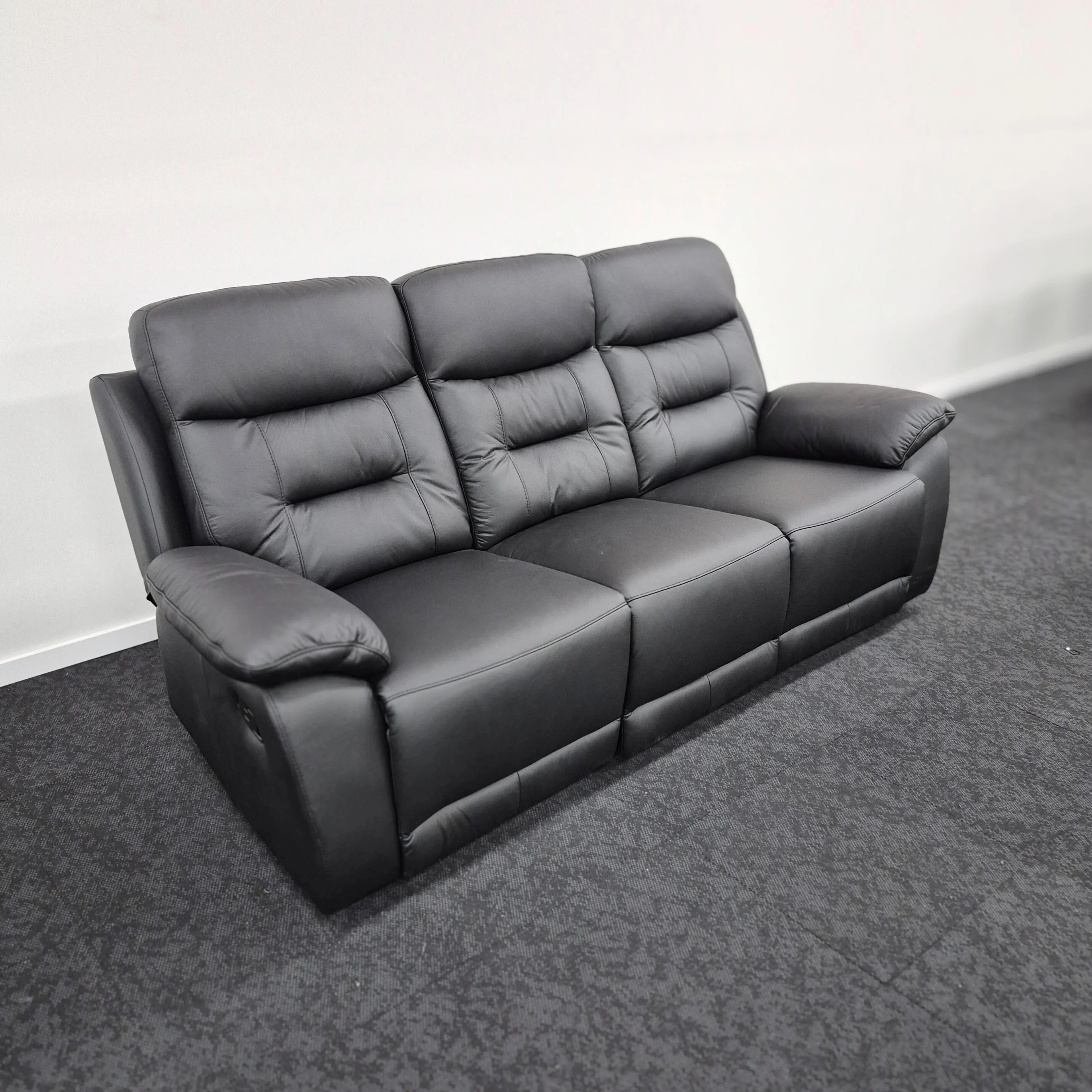 Three seater black leather recliner sofa with padded armrests and tufted cushions