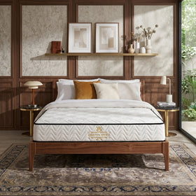 Sleep Essential V Pocket Spring Mattress displayed on a wooden bed frame in a stylish bedroom with warm wood paneling, decorative pillows, and natural light from a large window.