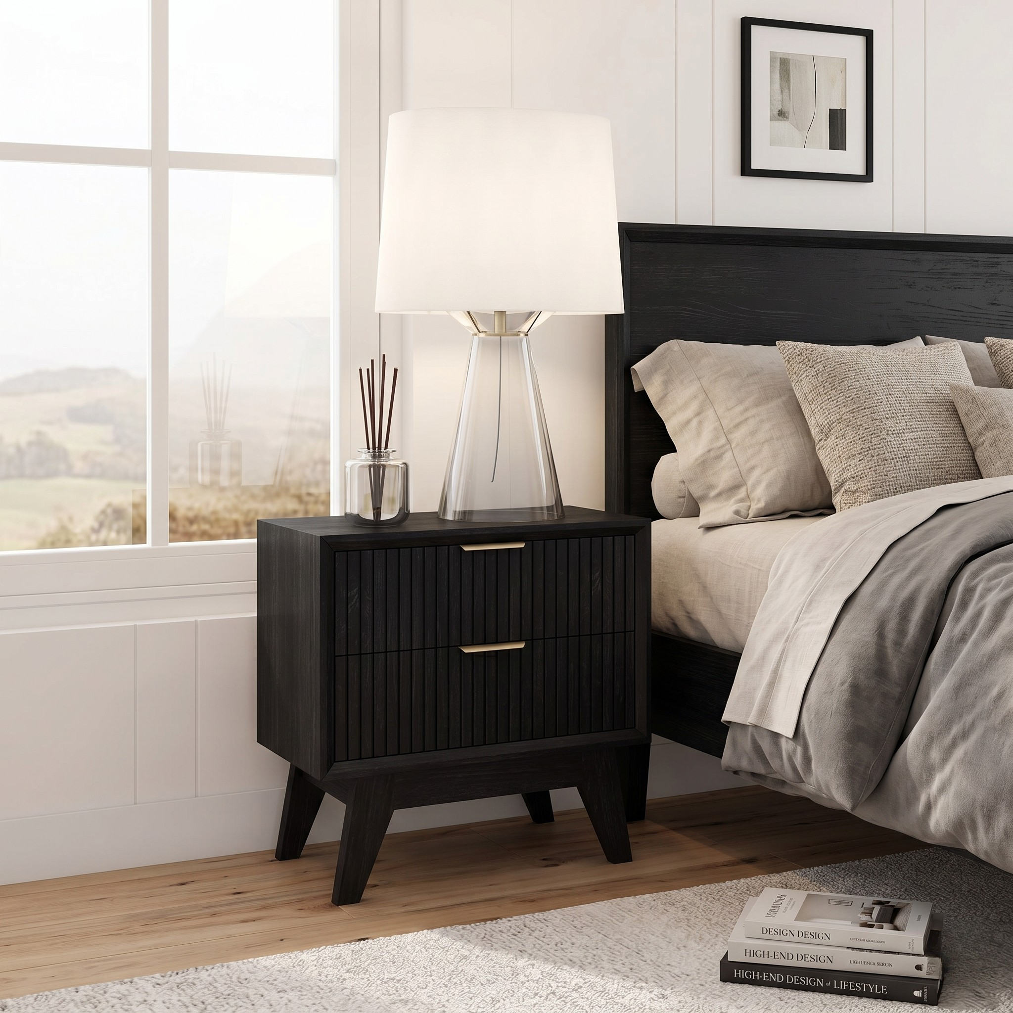 Black nightstand with lamp and decor next to a bed in a bedroom.