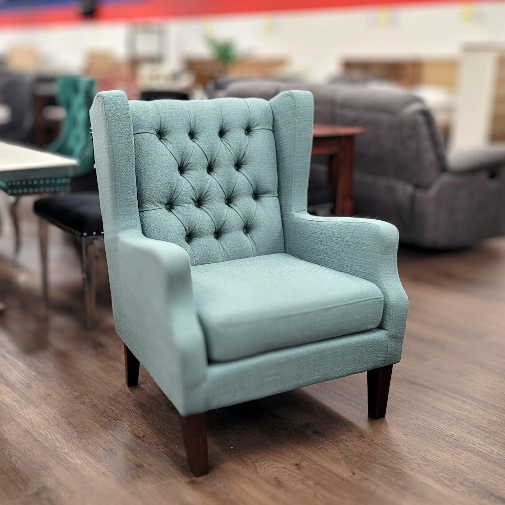 Light blue tufted armchair with wooden legs on showroom floor, modern lounge furniture