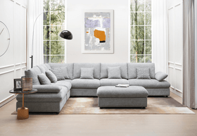 Modern living room with large grey sectional sofa, ottoman, and floor-to-ceiling windows