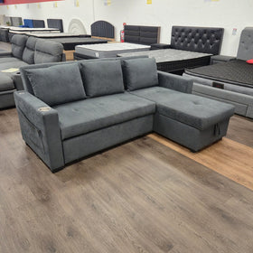 Oasis Pull Out Sofa Bed in dark grey fabric viewed from the side three-quarter angle in sofa mode, at The A2Z Furniture showroom