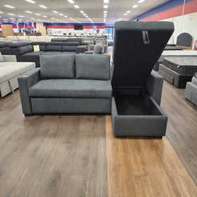 Oasis Pull Out Sofa Bed in dark grey fabric with the chaise storage compartment lid lifted open, at The A2Z Furniture showroom