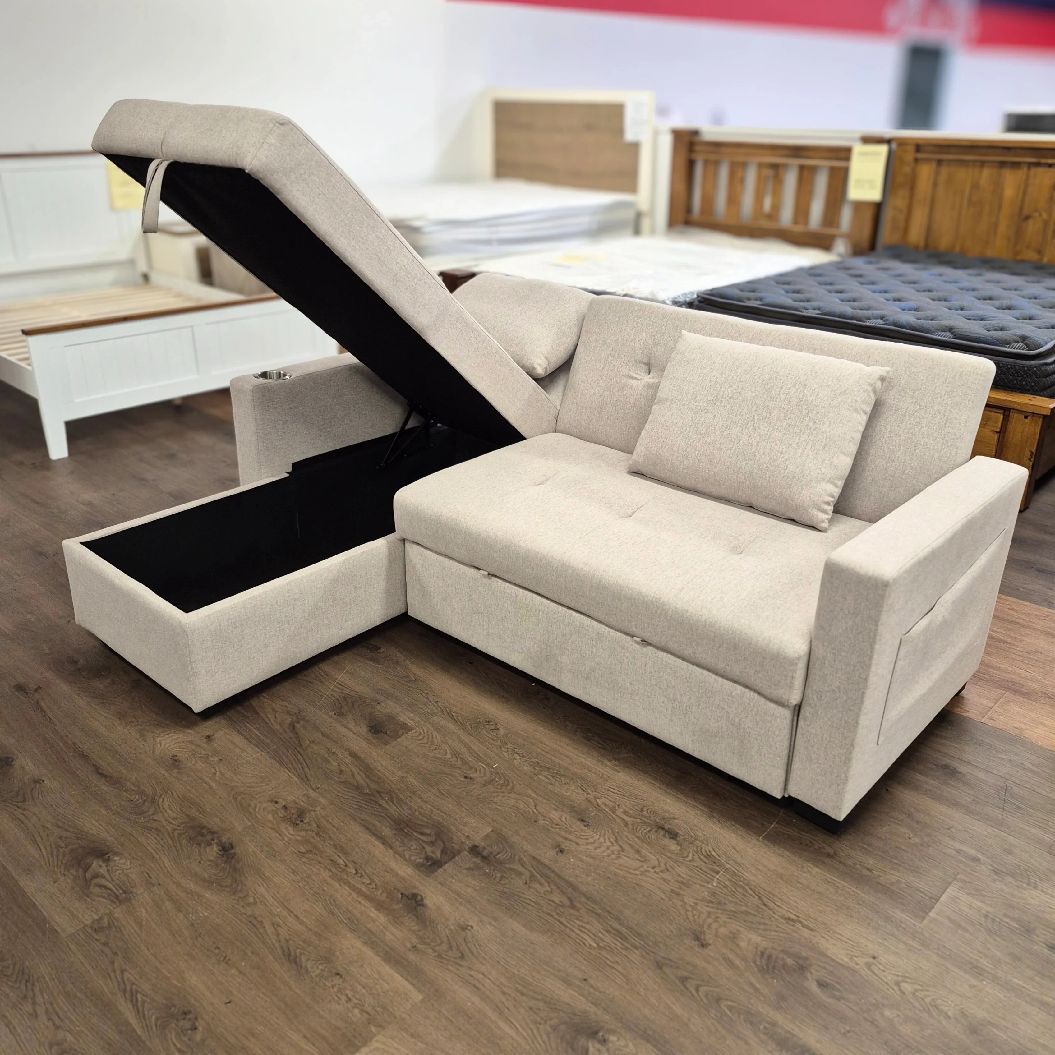 Beige fabric sofa bed with open storage chaise, modern design in furniture showroom
