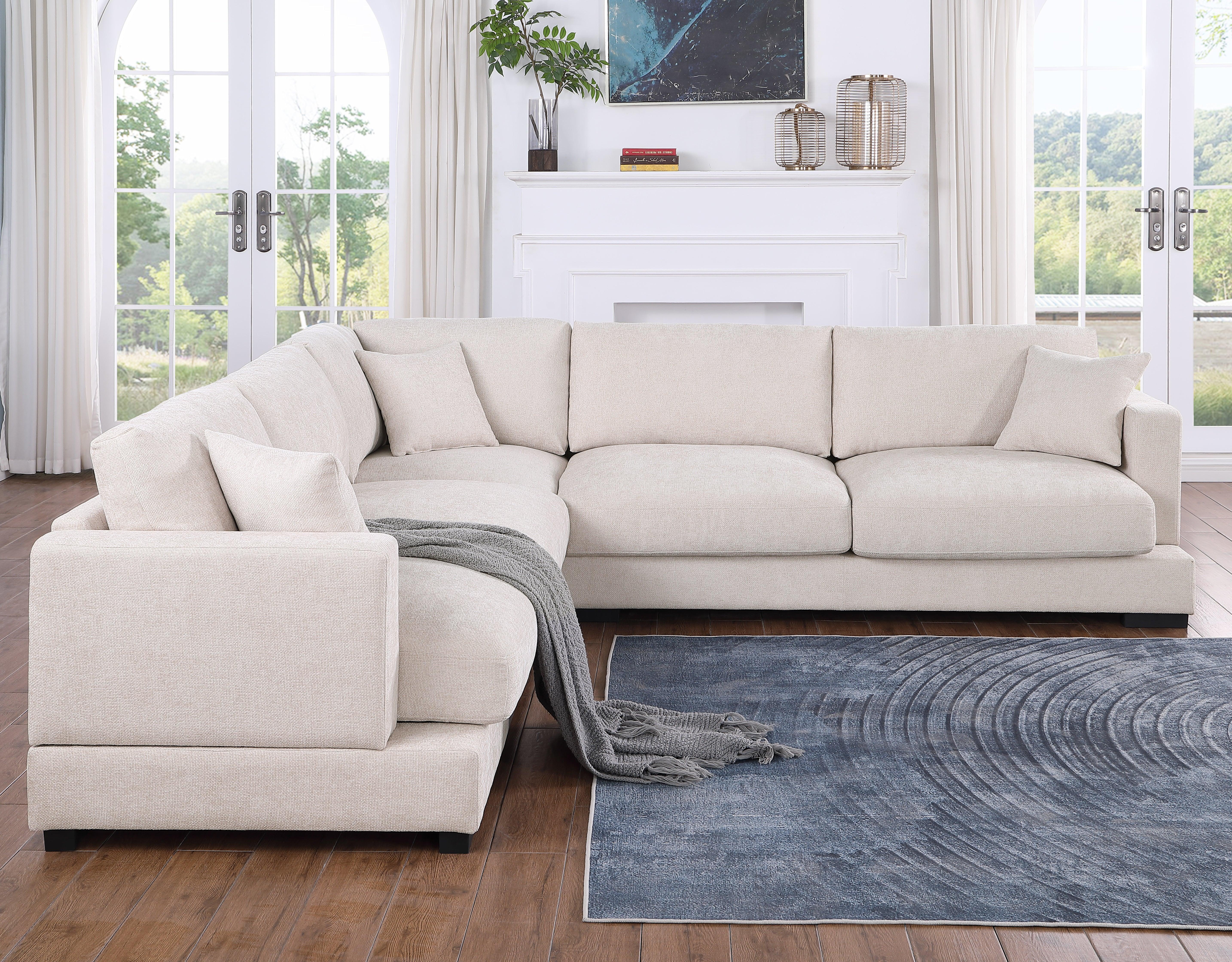 Modern beige sectional sofa with cushions and throw blanket in bright living room