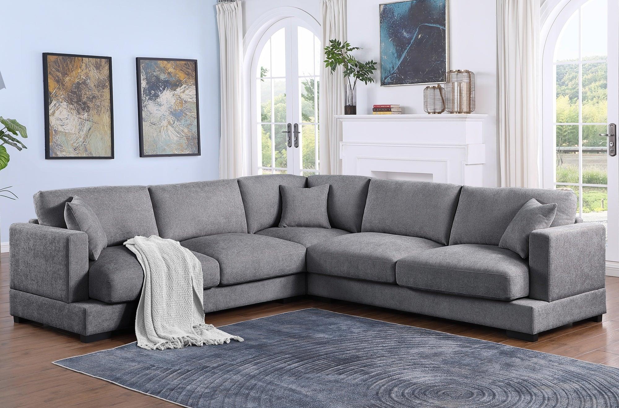 Modern living room with large grey sectional sofa, blue rug, and abstract wall art
