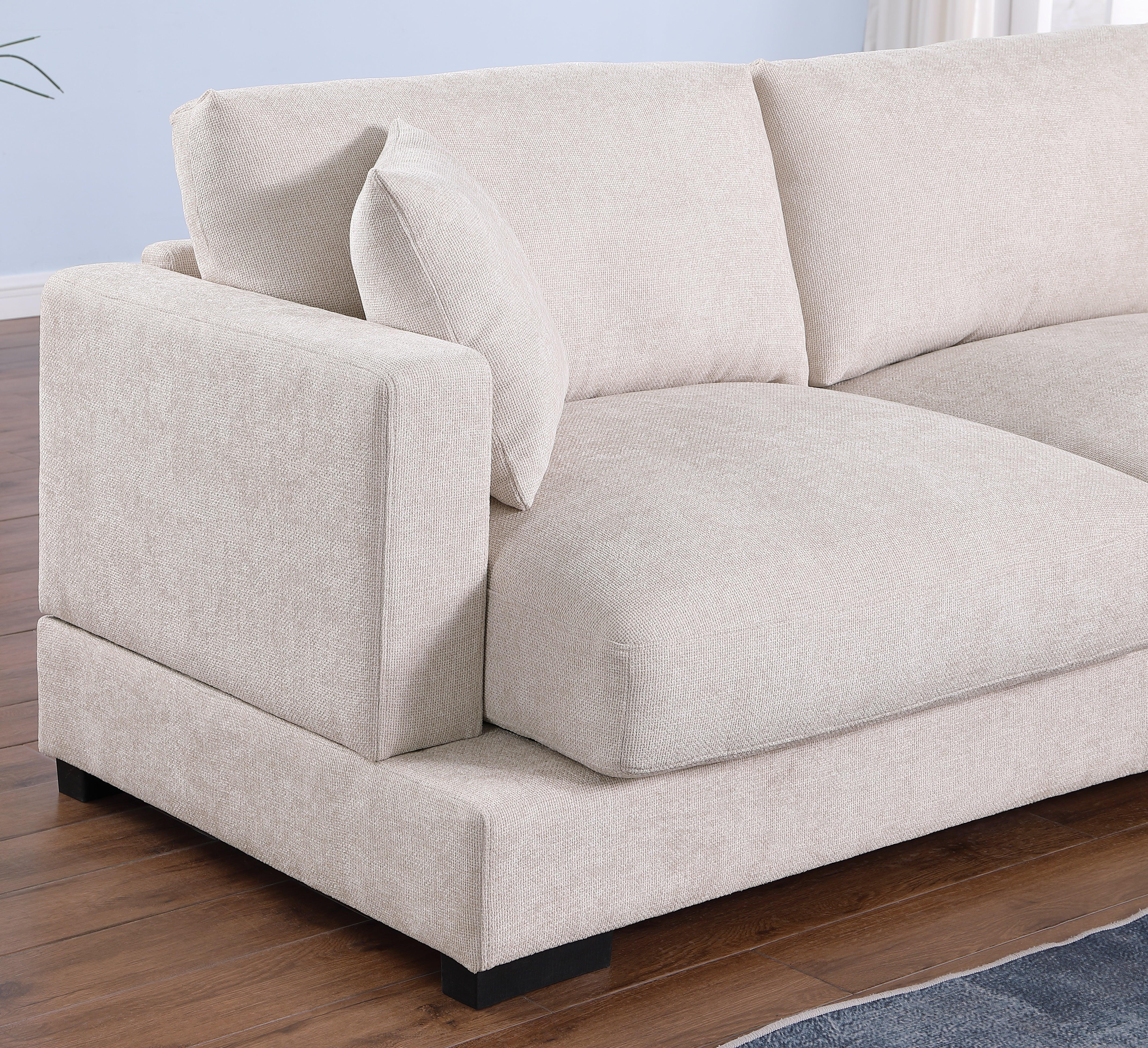 Modern beige fabric sofa with plush cushions on hardwood floor in bright living room