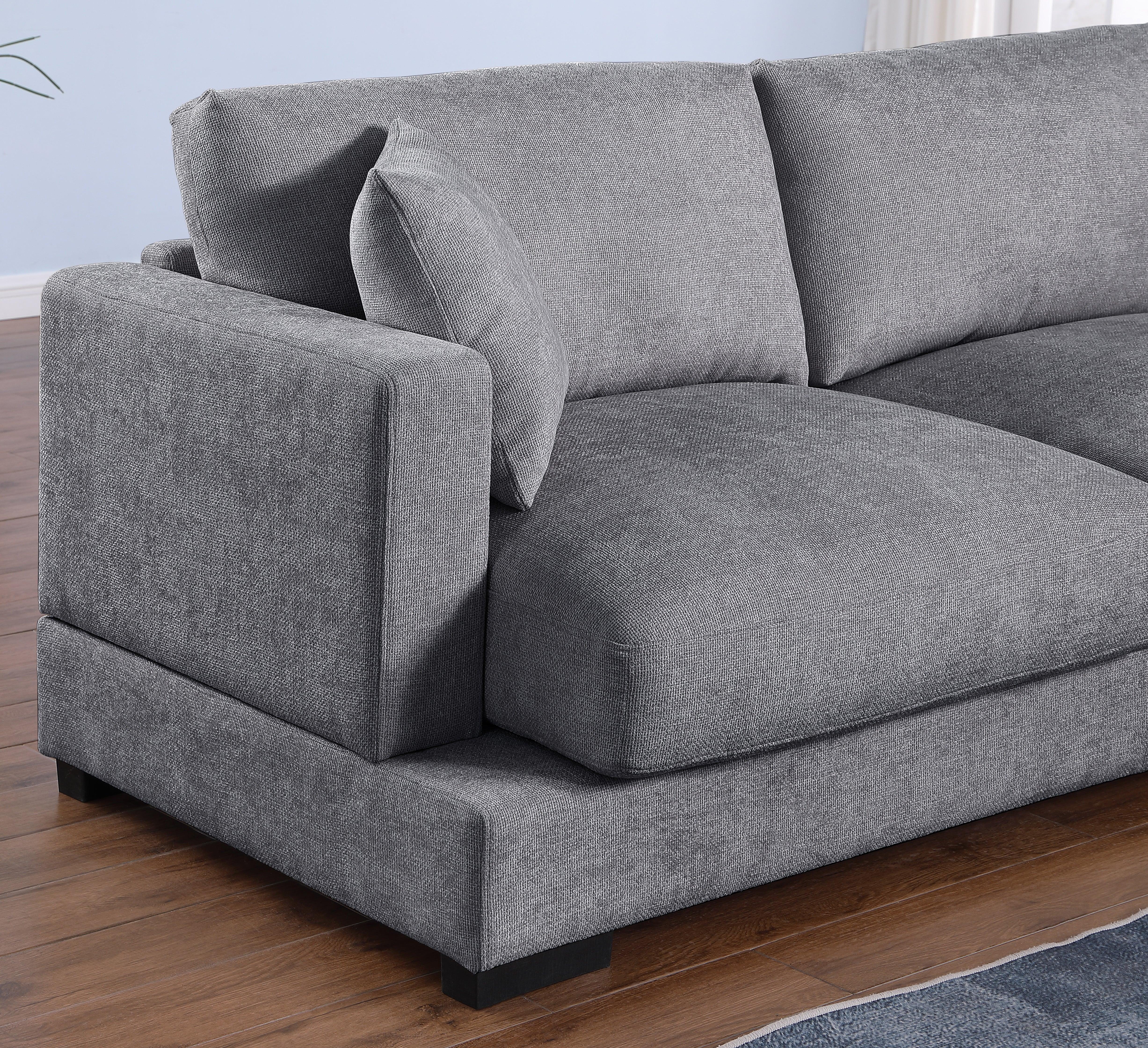 Modern grey fabric sofa with plush cushions on wooden floor in living room setting