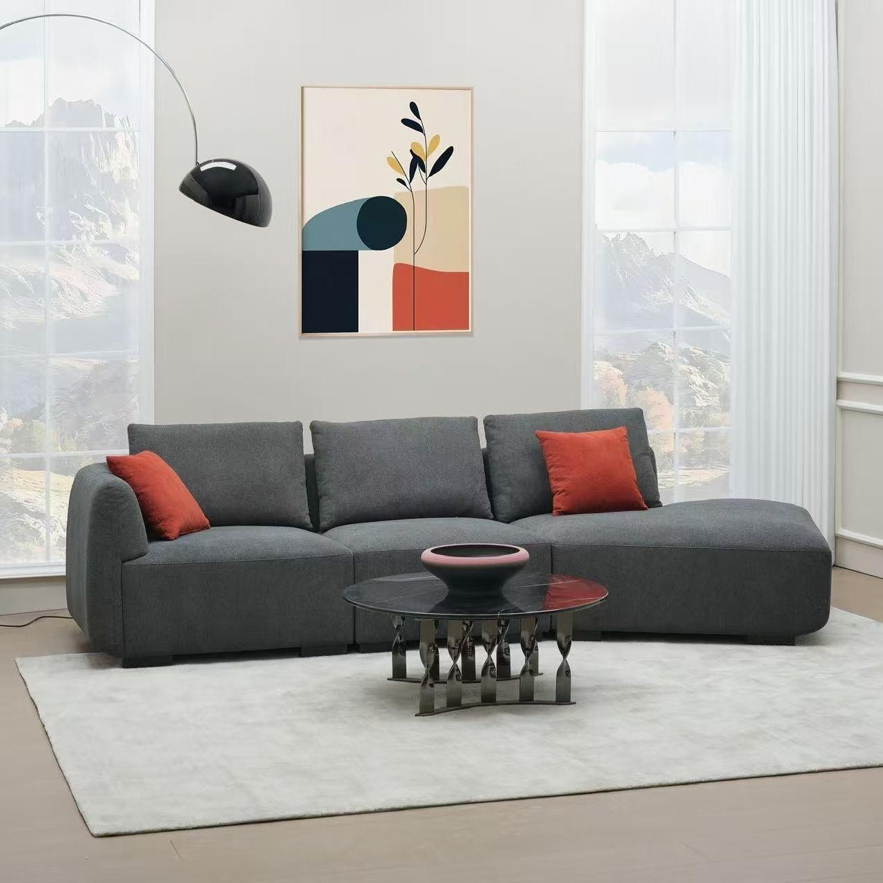 Modern grey sectional sofa with red accent pillows, black coffee table, and floor lamp in a bright living room.
