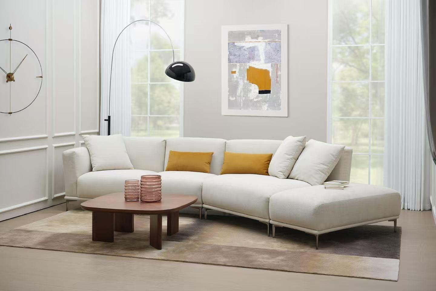Modern living room with large white sectional sofa, mustard cushions, wood coffee table, and wall art.